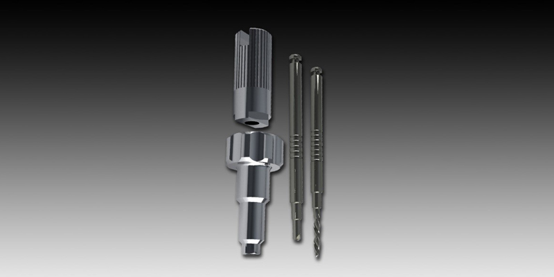 Components of Broken Screw Extraction Kit from Rhein 83®. Top left, the manual bur-holder device: bottom left, the centring guide, in the centre the “grip bur” and to the right the “special bur.” 